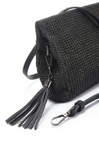 Borsa nera intrecciata con superficie testurizzata, dotata di una tracolla in pelle rimovibile e di un accento con nappina. Include una chiusura metallica.