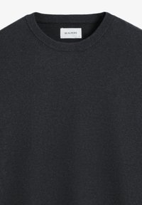 Mörkgrå tröja med rund hals, tillverkad av ett mjukt stickat material. Har en subtil logotyp på bröstet. Ribbad vid ärmslut och nederkant.