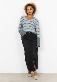 Grijs gestreepte trui met een v-hals, gecombineerd met een zwarte denim maxi-rok met een split aan de voorkant. Model draagt beige instappers.