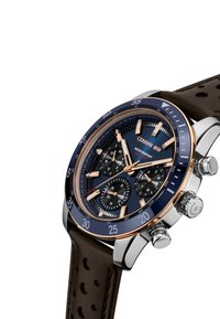 Montre chronographe avec un cadran bleu, des accents en or rose, un boîtier en acier inoxydable argenté et un bracelet en cuir brun texturé. Trois sous-cadrans visibles.