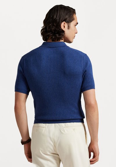 Μπλε, κοντομάνικο, ριγέ πόλο μπλουζάκι με γιακά και εφαρμοστό σχέδιο, συνδυασμένο με ανοιχτόχρωμο παντελόνι. Υφασμένο και διακριτικά ραμμένο.