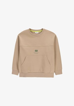 Beżowa bluza crewneck z przednią kieszenią kangurka i małym graficznym logo nad kieszenią z napisem „achieve.”