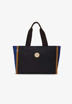 Czarna i niebieska prostokątna torba typu tote z brązowymi pionowymi paskami i okrągłym logo Kipling na środku, wyposażona w dwa czarne uchwyty.