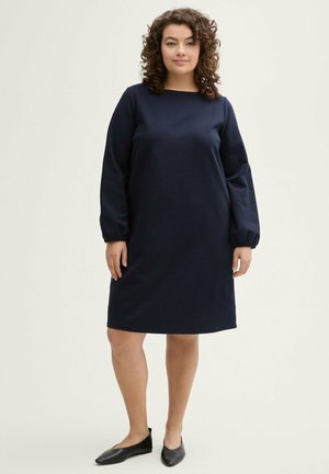 Marineblaues Langarmkleid mit gerader Silhouette und rundem Ausschnitt. Der Stoff ist glatt mit einer leichten Textur; die Ärmel sind an den Bündchen gerafft.