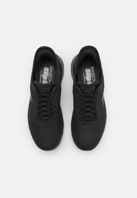 Zapatillas deportivas de malla negra con punta redondeada, cierre de cordones, cuello acolchado y suela texturizada para mayor tracción. Marca en la plantilla.