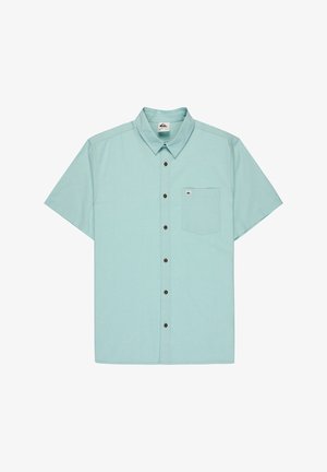Chemise bleu clair à manches courtes avec col, dotée d'une fermeture à boutons, de boutons marron et d'une poche poitrine gauche avec une étiquette logo.