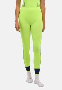 Neonowo zielone legginsy sportowe z teksturowanymi panelami i czarnym przeszyciem w akcentach; wysoki stan, dopasowany krój i tkanina odprowadzająca wilgoć.