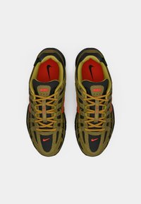 Nike sporta apavi ir aprīkoti ar olīvzaļo un melno sieta augšdaļu, spilgti sarkaniem akcentiem, uzkrītošām auklām un mīkstu sarkanu iekšpusi.