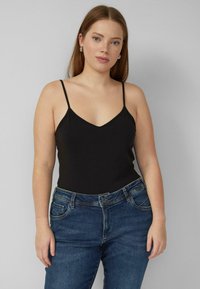 Czarny top na cienkich ramiączkach z dekoltem w kształcie litery V. Połączony z ciemnoniebieskimi dżinsami o klasycznym fasonie z pięcioma kieszeniami.