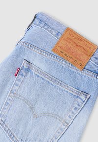 Hele sinise teksapükste nahast plaastriga, millel on silt "Levi Strauss & Co." ja kontrastse õmblusega, esitledes iseloomulikku tagatasku disaini.