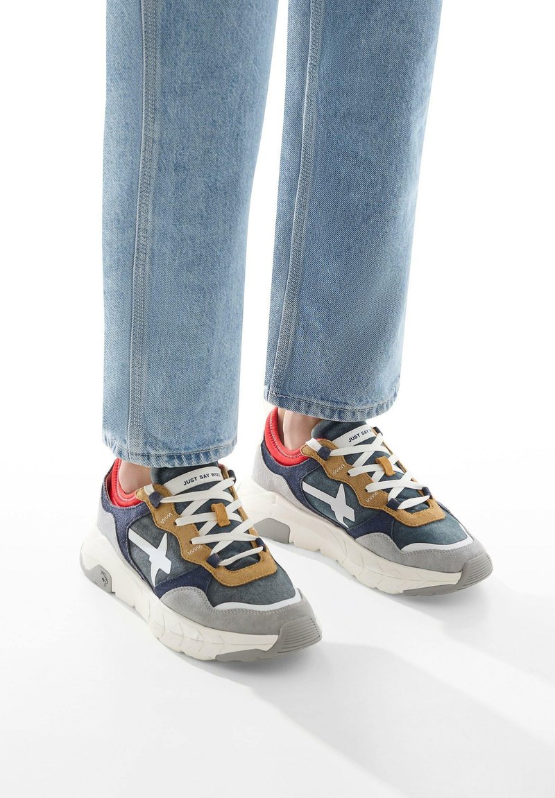 Sneakers sportivi in grigio, blu navy e beige con accentuazione a stella bianca; dotati di collare imbottito, chiusura con lacci e suola in gomma testurizzata.