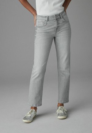 Jeans en denim gris avec une coupe droite, taille mi-haute et design à cinq poches, associés à un haut blanc côtelé et des baskets grises.