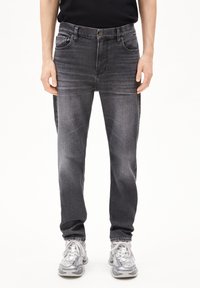 Donkergrijze denim jeans met een klassiek vijf-pocket ontwerp, met subtiele vervaging en een rechte pijp, in combinatie met grijze sneakers.