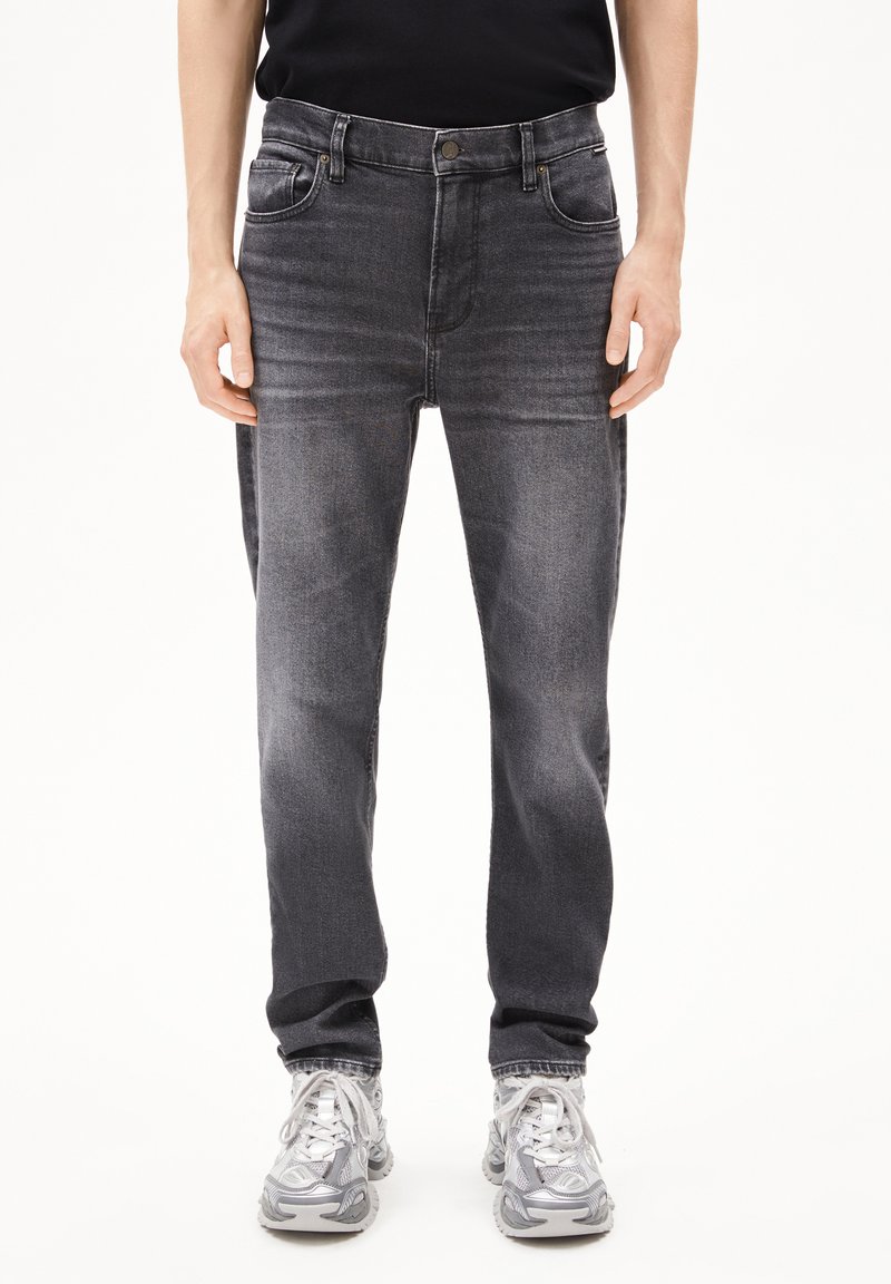 Donkergrijze denim jeans met een klassiek vijf-pocket ontwerp, met subtiele vervaging en een rechte pijp, in combinatie met grijze sneakers.