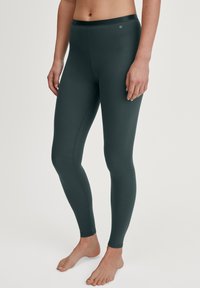 Collants vert fonc é en tissu extensible, avec une texture lisse et une large taille. Pas de motifs visibles ni de détails en quincaillerie.