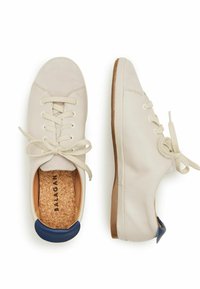Zapatillas de cuero blancas con puntera beige, cierre de cordones, plantillas de corcho y un acento azul en el talón. Textura suave y diseño de perfil bajo.