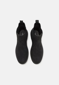 Botines negros de ante con textura suave, que cuentan con paneles laterales elásticos y un diseño de punta redonda.