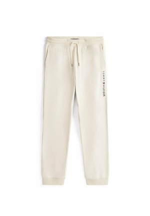 Pantaloni della tuta color crema realizzati in morbido tessuto, con vita elasticizzata e cordino, e un logo stampato lungo la gamba sinistra.