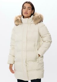 Bílá péřová bunda s odnímatelnou kapucí s kožešinovým lemováním, s prošívanou výplní a předními kapsami. Měkká textura a délka po kolena.