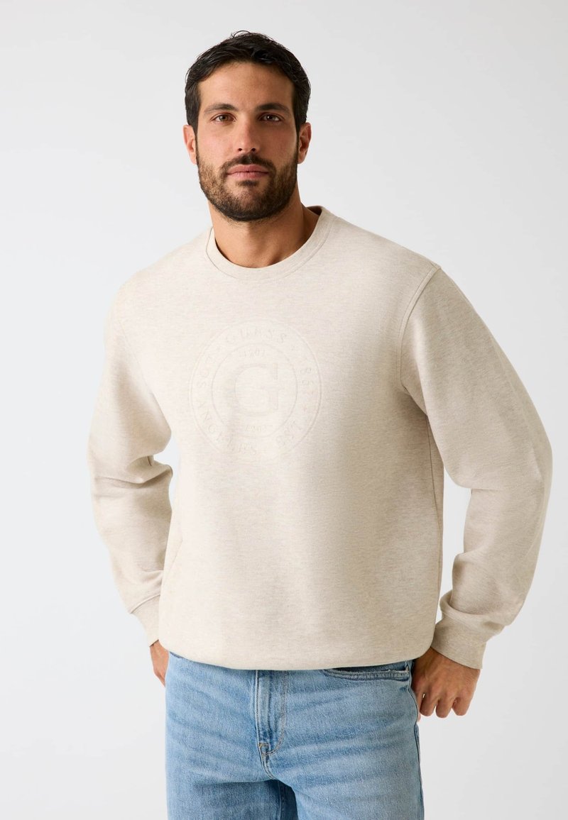 Lichtbeige sweatshirt met een ronde hals en lange mouwen. Voorzien van een getextureerd logo in het midden. Gemaakt van katoenmenging, met een losse pasvorm.