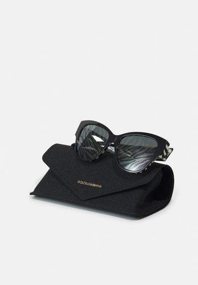 Ochelari de soare negri, de dimensiuni mari, cu lentile întunecate, având un model de zebra pe brațe. Însoțiți de o carcasă neagră cu siglă aurie.