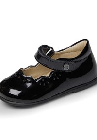 Zapato Mary Jane de charol negro con bordes festoneados y detalles florales recortados. Cuenta con una correa de velcro y suela de goma.