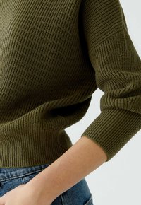 Olivgrüner, gerippter Strickpullover mit taillierter Passform und dreiviertellangen Ärmeln, der einen strukturierten Stoff und eine enge Passform präsentiert.