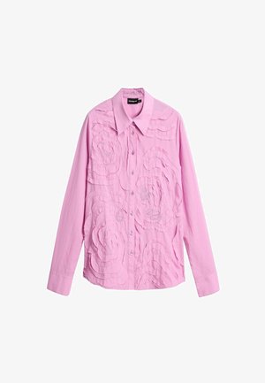 Roosa pikakätisega särgiga, millel on krae, millel on kihilised lillemustrid ja hõbedased nööbid esiosas. Pehme puuvillane kangas.