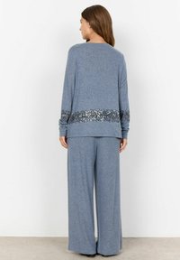 Lichtblauw loungewear set met een langemouwen top voorzien van een zoom met paillettenaccent en ontspannende, losse broek van zachte, gestructureerde stof.