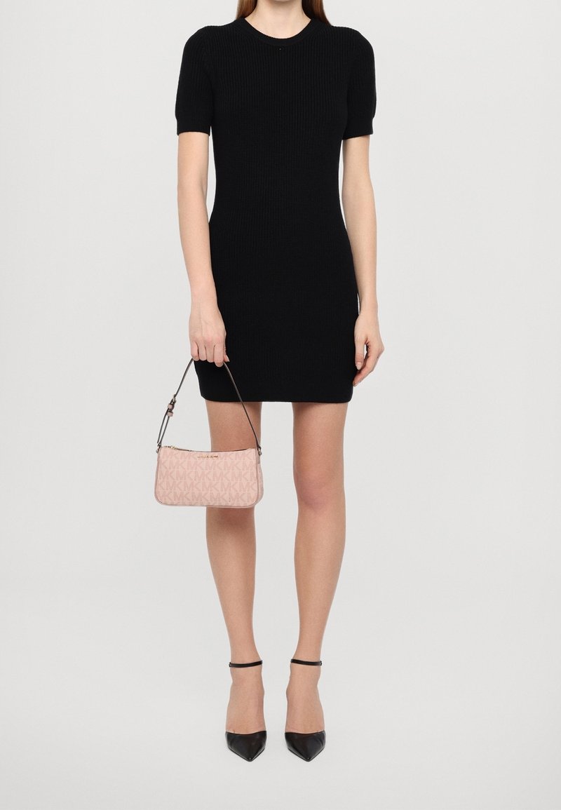 Abito nero a costine con maniche corte abbinato a una borsa rosa con motivo e décolleté nere a punta. Design elegante e aderente.