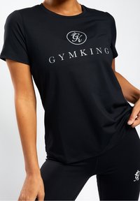 Černé tričko s krátkým rukávem vyrobené z hladké tkaniny, s červeným logem "GYMKING" a kruhovým emblémem na hrudi, s volným střihem.