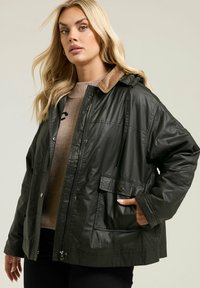 Veste imperméable vert foncé avec une fermeture éclair à l'avant, des poches à boutons et un col en velours côtelé marron. Les cordons de la capuche sont visibles, montrant un ajustement décontracté.