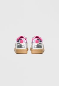 Baskets argentées métalliques avec accents roses, forme arrondie, semelle en caoutchouc texturée et col rembourré. Dotées d'une fermeture à lacets et d'un talon renforcé.
