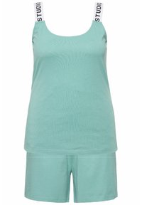 Ensemble top en mint et short en tissu doux. Le top est doté de bretelles épaisses avec le texte "STUDIO". Look simple et décontracté sans motifs.