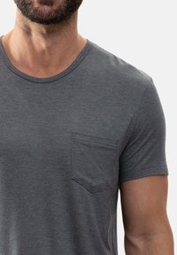 Harmaa lyhythihainen t-paita, jossa on pyöreä pääntie ja suorakulmainen rintatasku. Pehmeä materiaali ja rento istuvuus.