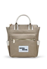 Mochila de lona beige con asas blancas, bolsillo frontal con cremallera y etiqueta "BOSA NOVA". Presenta un diseño estructurado y una textura duradera.