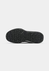 Outdoor shoe with a rugged black rubber outsole featuring multidirectional lugs for traction. The design includes a smooth upper.