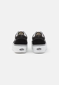 Černé semišové platformové tenisky s bílými gumovými podrážkami a stehy. Mají polstrovaný límec a logo Vans na patě.