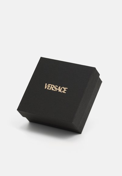 Caja rectangular negra con un acabado texturizado. Presenta el logo dorado "VERSACE" en la parte superior, con un cierre magnético. Diseño compacto.