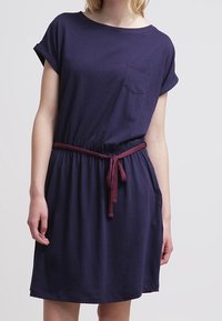 Granatowa sukienka z krótkim rękawem, wykonana z miękkiego materiału. Posiada kieszeń z przodu oraz bordowy pasek ze sznurkiem w talii. Casualowy krój.