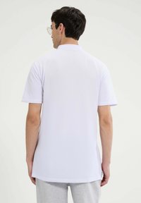 Biała koszulka polo z krótkim rękawem, z prążkowanym kołnierzykiem i prostym dołem. Wykonana z lekkiego materiału, charakteryzuje się gładką teksturą.