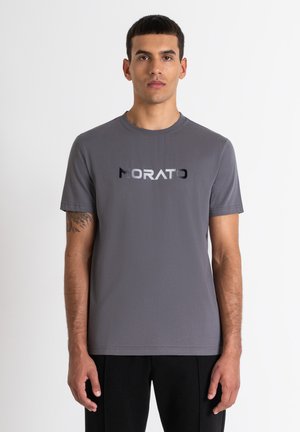 Camiseta gris de manga corta hecha de un tejido suave, con un logotipo en contraste de negro y plata "MORATO" en el pecho.