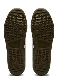 Černobílé podešve tenisek s texturovaným gumovým povrchem, obsahující cik-cak vzory, dvě kruhové segmenty a detaily loga.