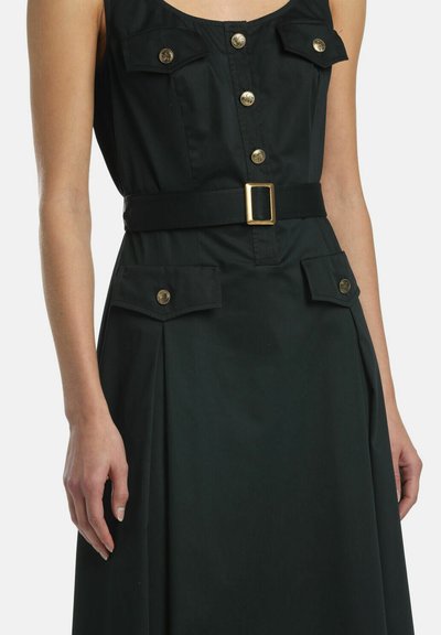 Ärmelloses schwarzes Kleid mit goldenen Knöpfen, zwei Brusttaschen, zwei Hüfttaschen und einem schwarzen Gürtel mit einer goldenen rechteckigen Schnalle.