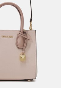 Borsa a tracolla in pelle rosa chiaro con design strutturato, dettagli in oro e un lucchetto decorativo. Presenta doppi manici e una tracolla removibile.