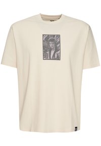 Crème-kleurig katoenen t-shirt met een ronde hals en korte mouwen, met een geprinte zwart-wit afbeelding ingelijst op de voorkant.