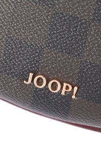 Brązowy portfel ze skóry o teksturowanej powierzchni z ciemnym wzorem w kratę oraz detalem logo "JOOP!" w kolorze różowego złota w prawym dolnym rogu.
