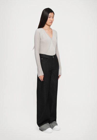 Light gray ribbed long-sleeve top with a V-neck, paired with high-waisted black wide-leg jeans and white slip-on shoes.