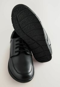 Chaussures en cuir noir avec un bout rond, système de laçage et semelles en caoutchouc texturé avec un motif de crampons pour une meilleure adhérence.