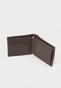 Portefeuille en cuir marron avec plusieurs emplacements pour cartes et un compartiment, présentant une texture lisse et des bords cousus. Accents rouge et blanc à l'intérieur.